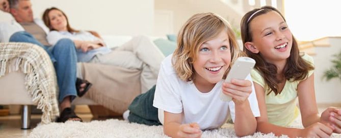 Family watching television, and young girls changing the channel with remote.