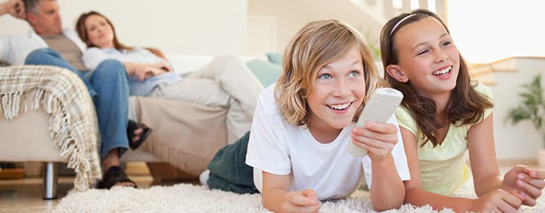 Whole-Home Humidifier Family watching television, and young girls changing the channel with remote.