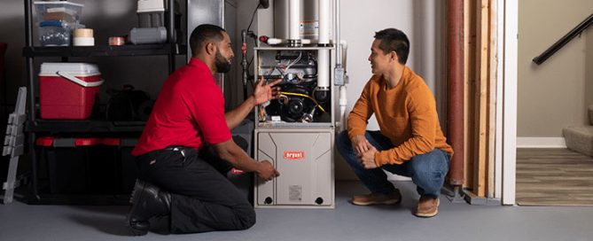 Tech shares regular furnace maintenance plan with homeowner in basement.