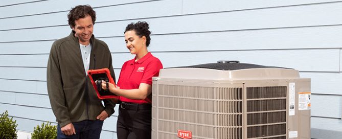 Tech in red shirt uses tablet to show homeowner the ins and outs of a new A/C installation.