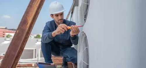 air conditioner technician checking air conditioner web | River City Heating & Air Conditioning